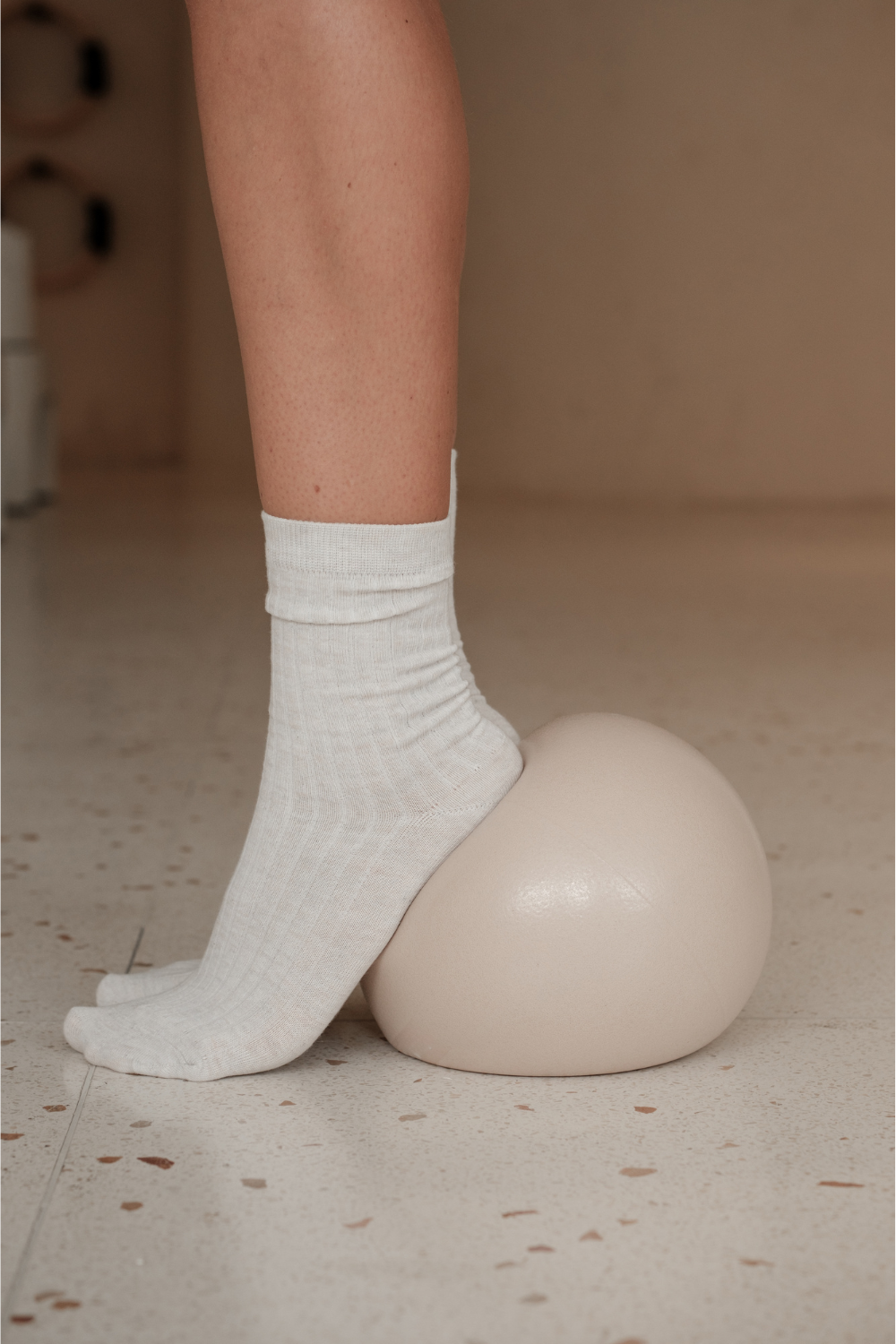 Femme qui s'entraine avec un ballon de Pilates et ses chaussettes antidérapante.